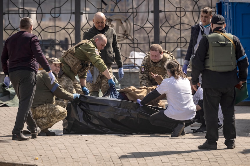 I soldati ucraini rimuovono i corpi dopo l'attacco missilistico