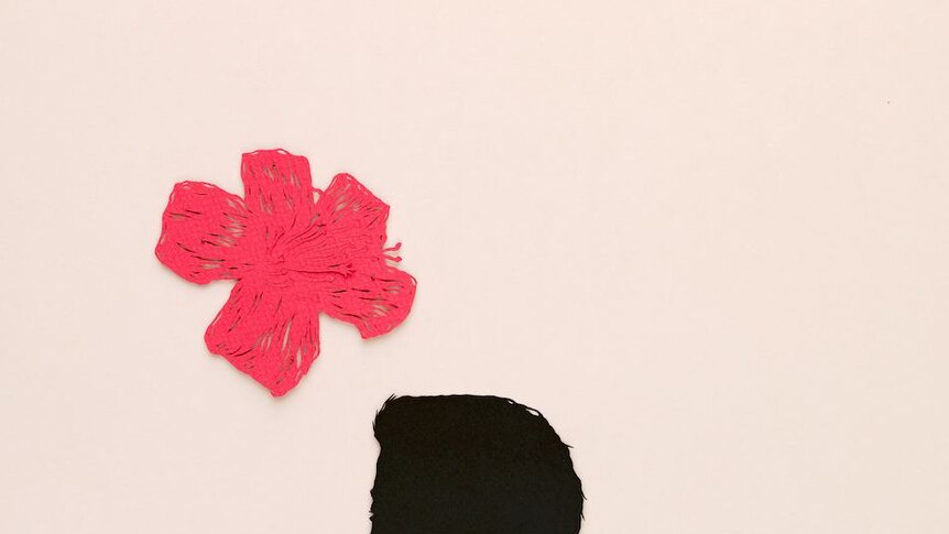 A paper cut out of a man's silhouette, a flower and pea cock feather