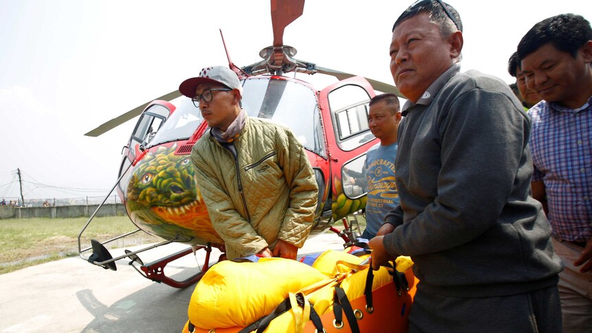 Sherpas carry a body bag from a helicopter.