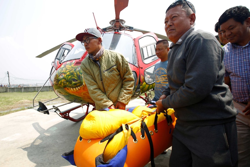 Sherpas carry a body bag from a helicopter.