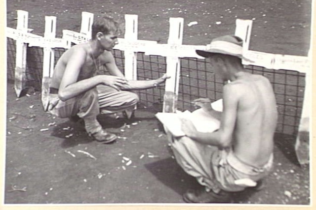 Soldiers identifying crosses at grave sites 