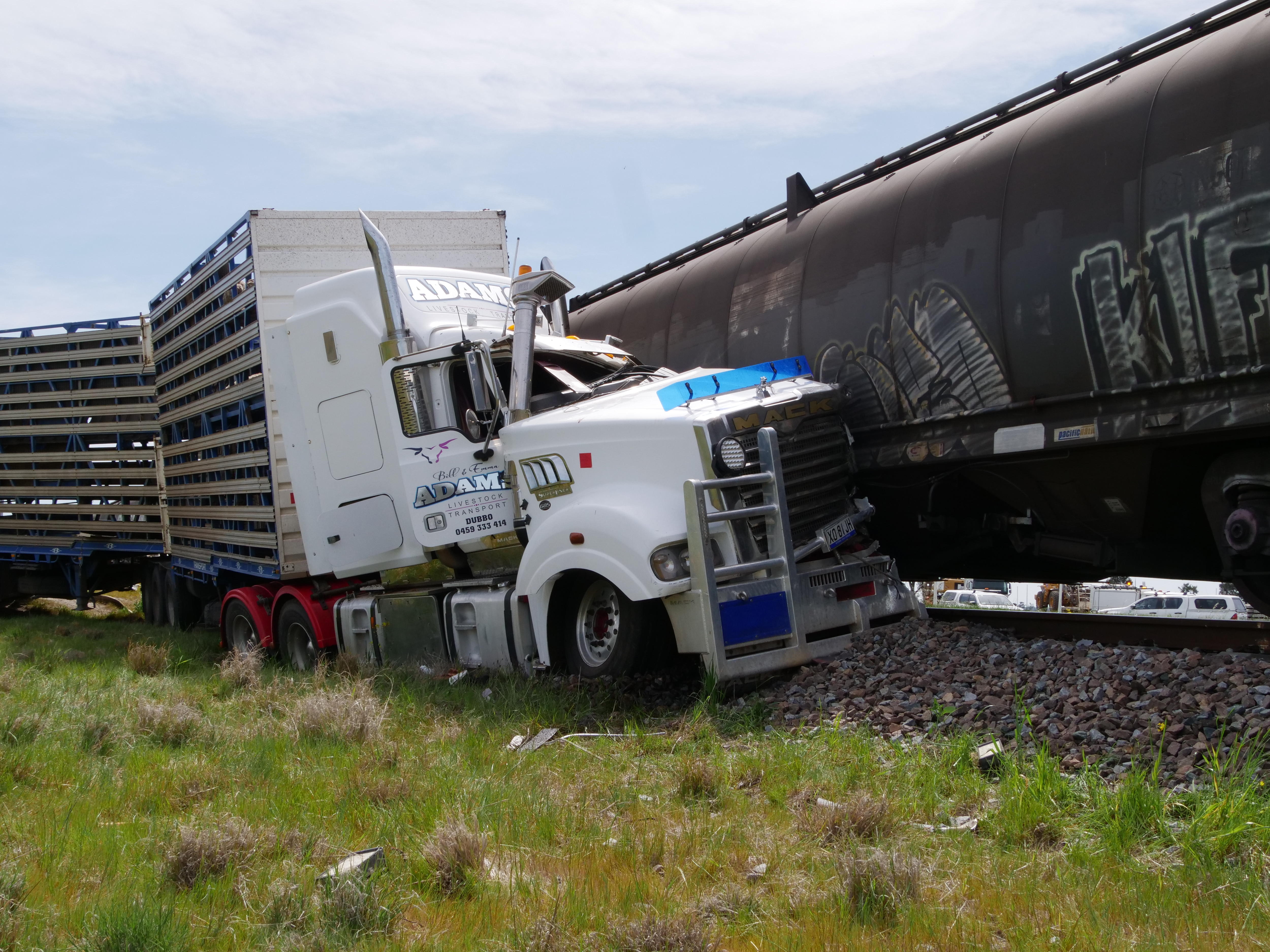 The front of a truck sits crashed into a train. 