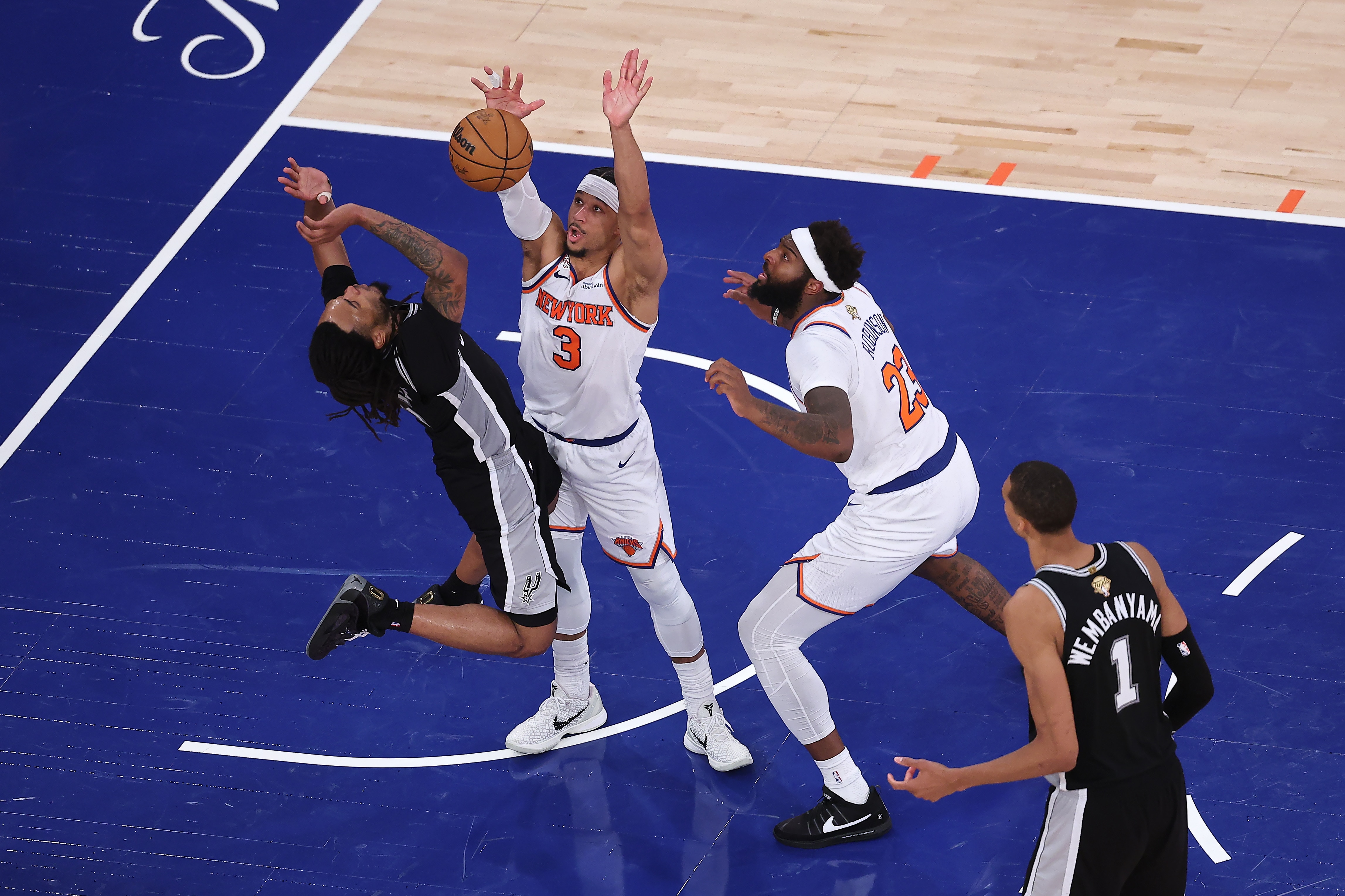 A San Antonio NBA player's shot is blocked by a New York Knicks player in a finals game.
