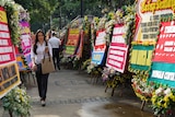 A woman walks through the many floral arrangements, seemingly on her way to work