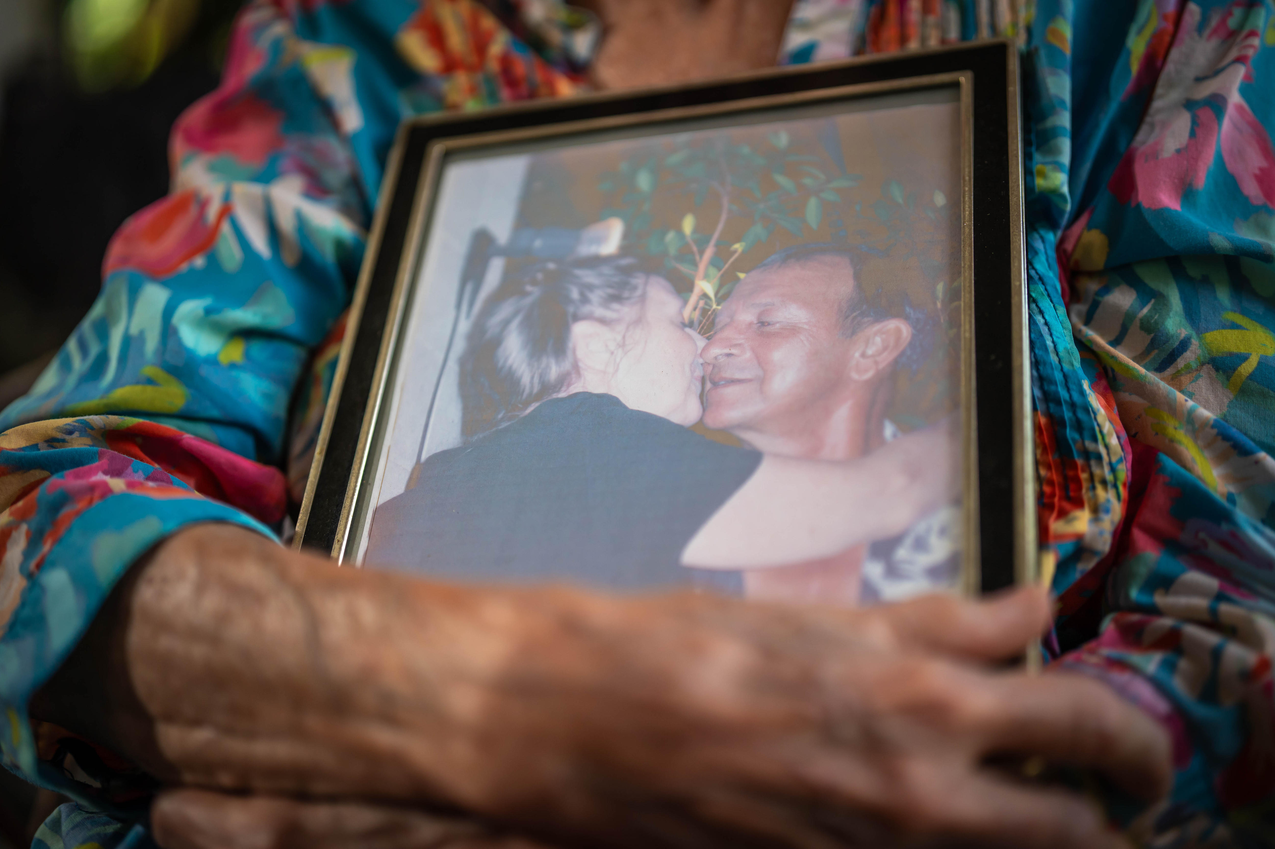 A close up shot of a photo frame featuring a young Carolyn Marriott kissing the cheek of her partner John Bhana.