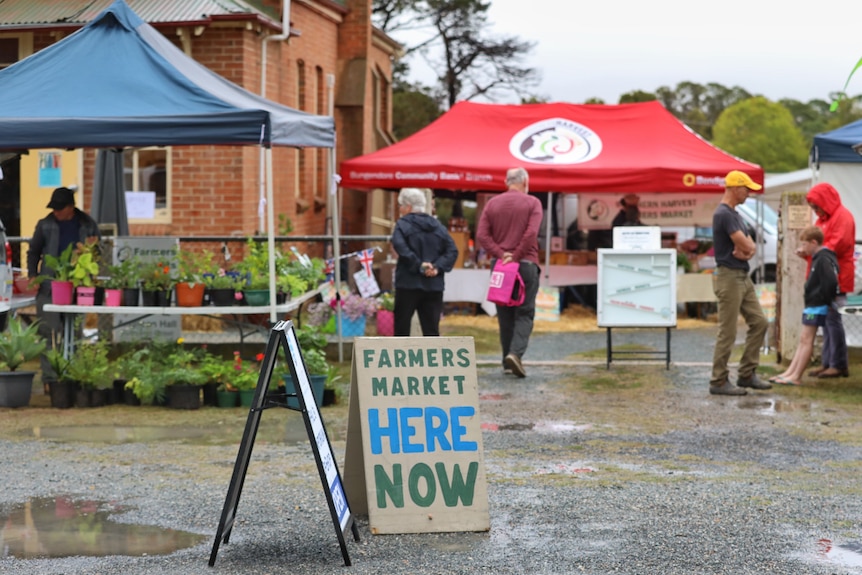 Grey skies and rain loom over the brightly coloured tents at the Southern Harvest Farmers Market in Bungendore.