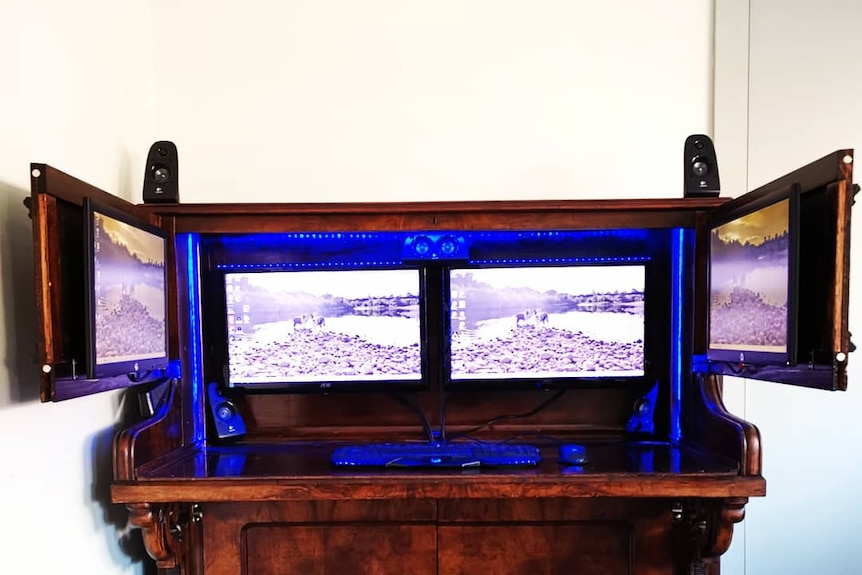 A piano that has been turned into a cabinet with 4 computer screens rigged in it