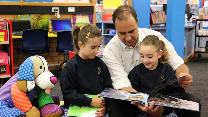 Twins Angelina (left) and Dion (right), 5, with dad Nick Kattas at Fraser Primary School library.
