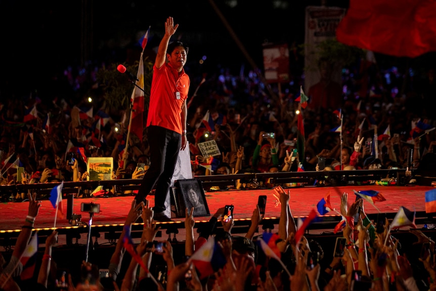 A man waves from on stage.