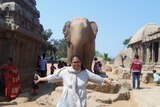 a woman with arms spread in front of an elephant statue