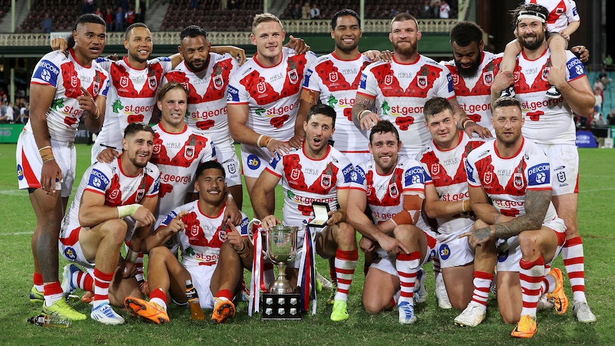 St George Illawarra NRL players pose for a photo with a trophy after their win over Sydney Roosters on Anzac Day.