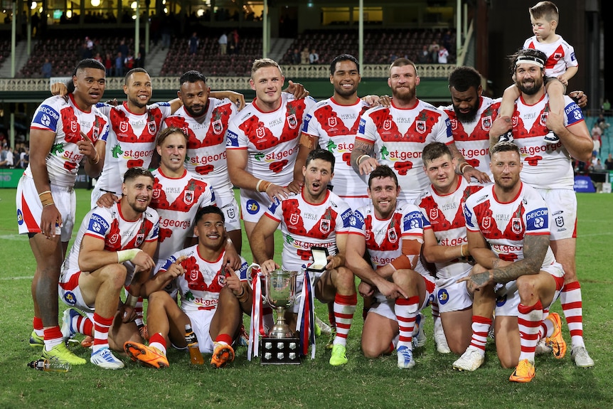 St George Illawarra NRL players pose for a photo with a trophy after their win over Sydney Roosters on Anzac Day.