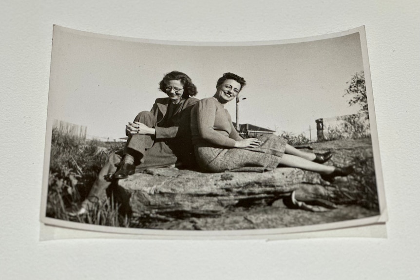 Two women sitting on a rock in a photograph.