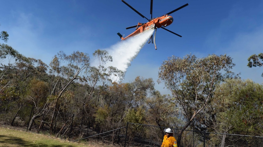 A firefighter looks on as air crane Elvis drops water at the Linksview Road fire near Faulconbridge, in the Blue Mountains 23/10/2103