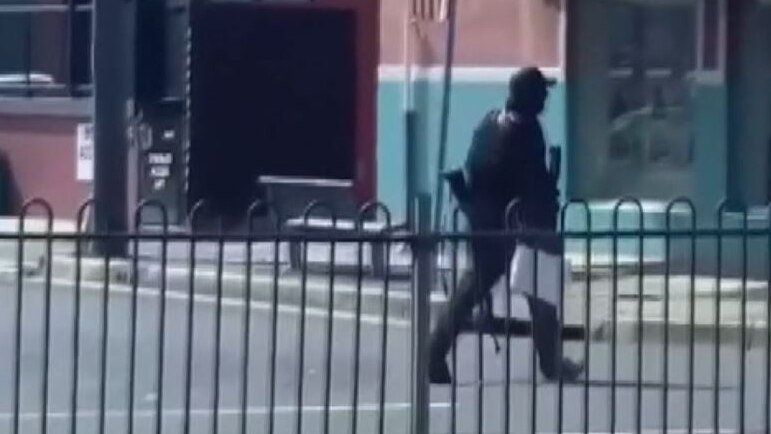 man in black walking with a gun.