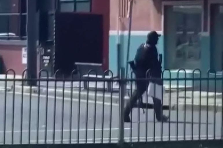 man in black walks across a street.