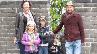 A family stands next to a stone wall.