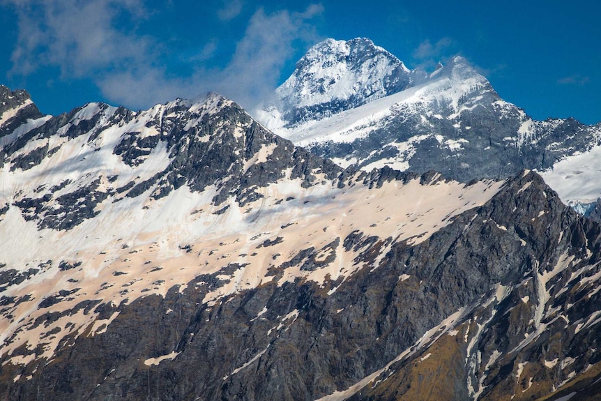 A mountain range is covered by snow that has a red tinge.