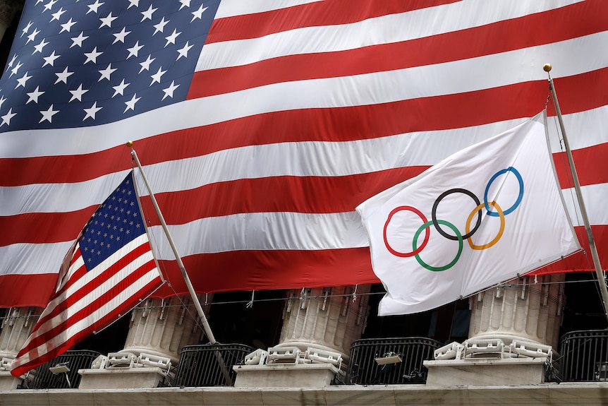 Las banderas de EE. UU. y los Juegos Olímpicos ondean frente a la Bolsa de Valores de Nueva York