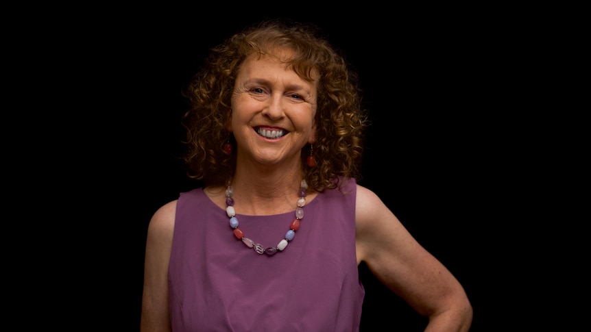 A smiling woman in front of a black background.