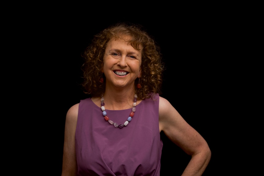 A smiling woman in front of a black background.
