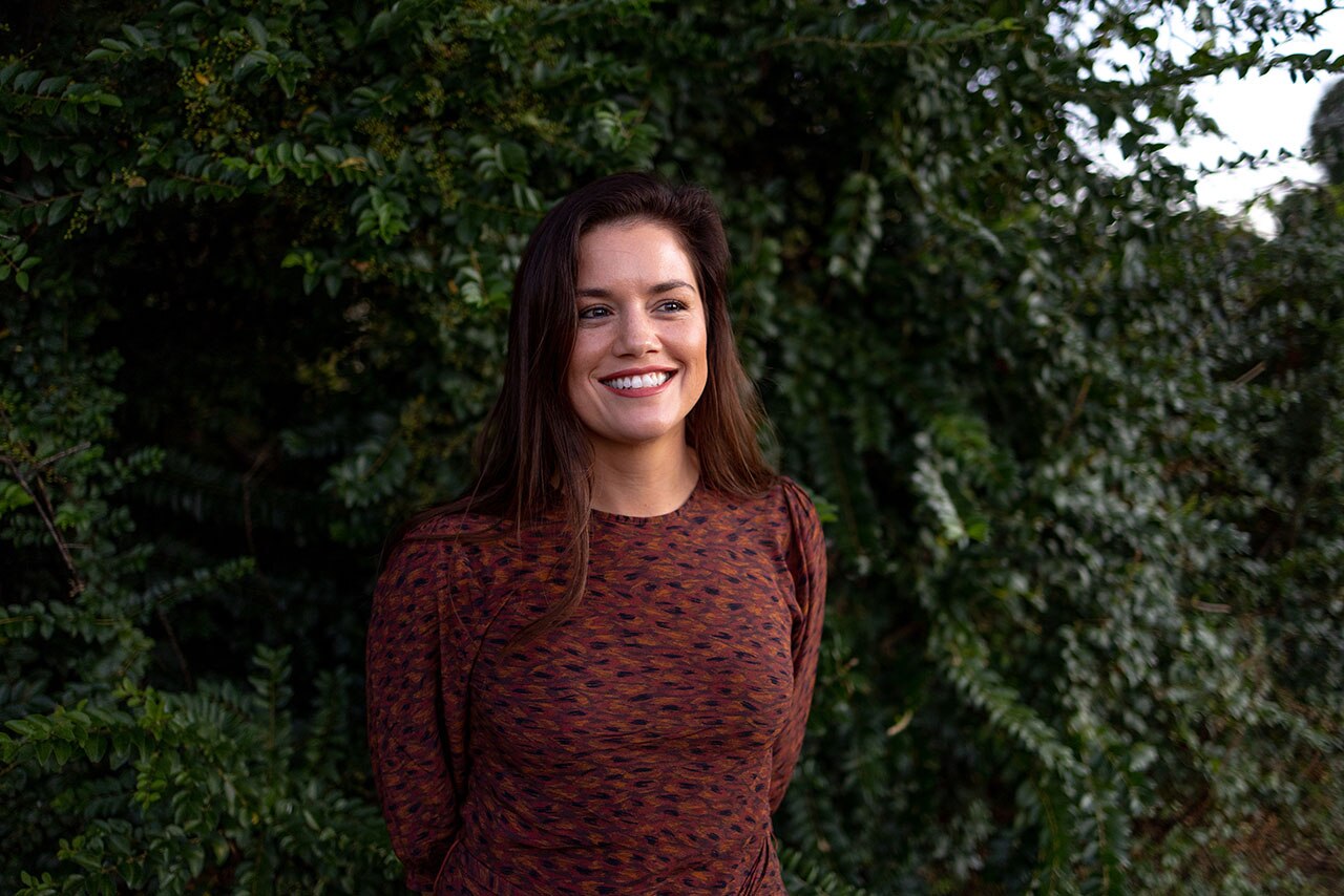 A woman smiling and looking in the distance towards the right.