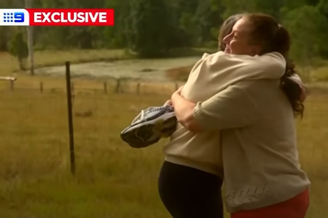 Two women hug in a field