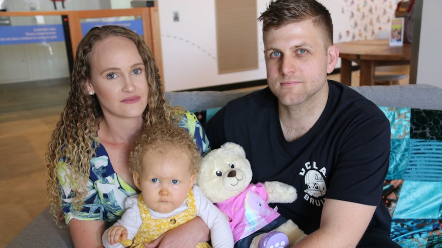 Two you parents hold their daughter Wynter at a medical clinic.