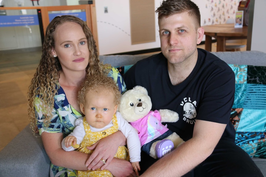 Two you parents hold their daughter Wynter at a medical clinic.