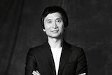 Queensland Ballet's artistic director Li Cunxin stands with arms crossed, smiling for the camera.