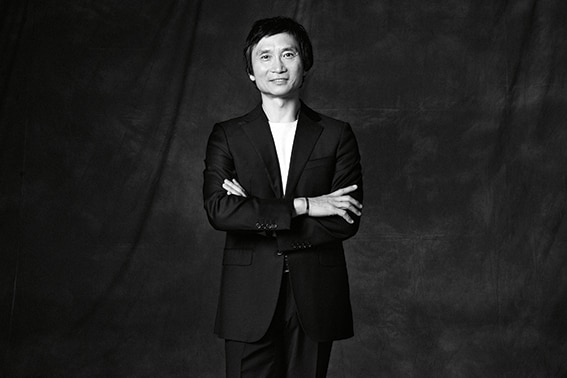 Queensland Ballet's Li Cunxin stands smiling,with his arms crossed
