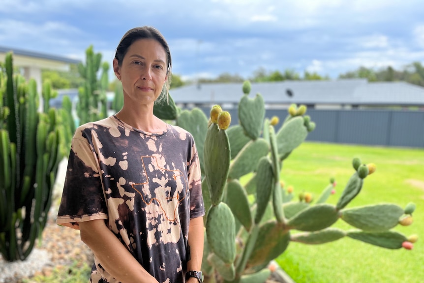 A woman stands in a suburban home in front of cacti.