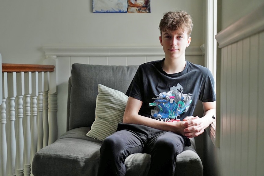 A teenage boy sitting on a couch.