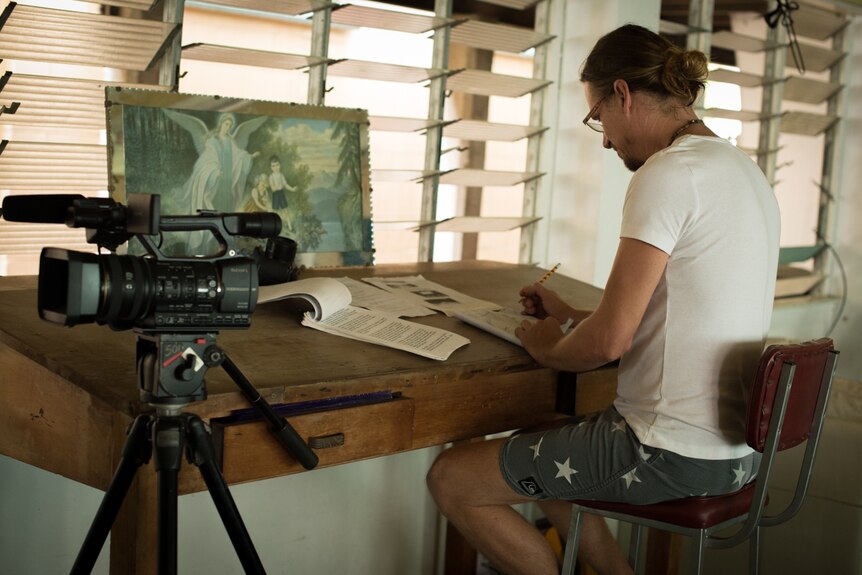 A man sits at a drawing table editing a film script.