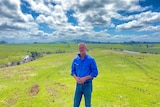 A picture of a farmer on his property with a river in the background 