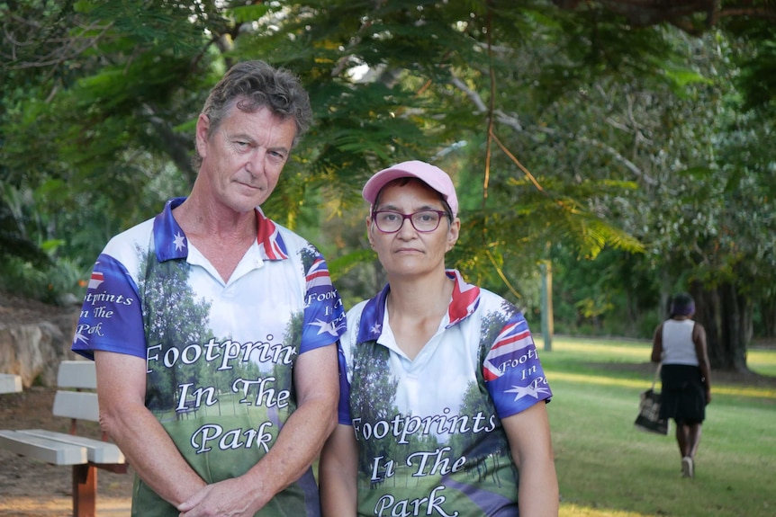 A man and a woman stand side by side at a barbecue in a park