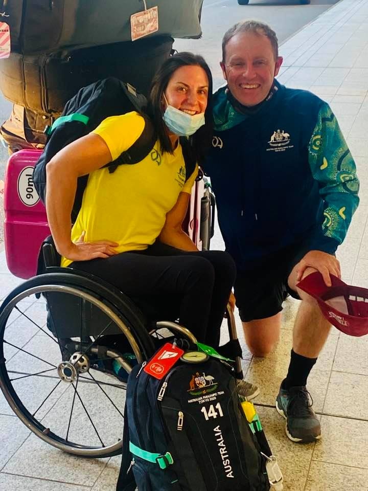 A smiling wheelchair athlete and her husband at an airport.