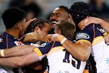 Brumbies Super Rugby AU players embrace as they celebrate a try against the Melbourne Rebels in Canberra.
