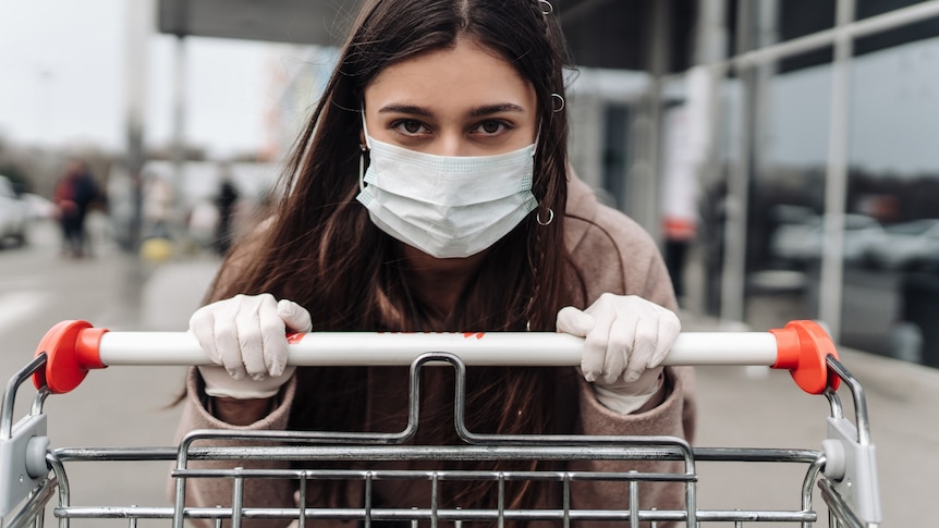A young woman wearing a surgical mask pushing a trolley