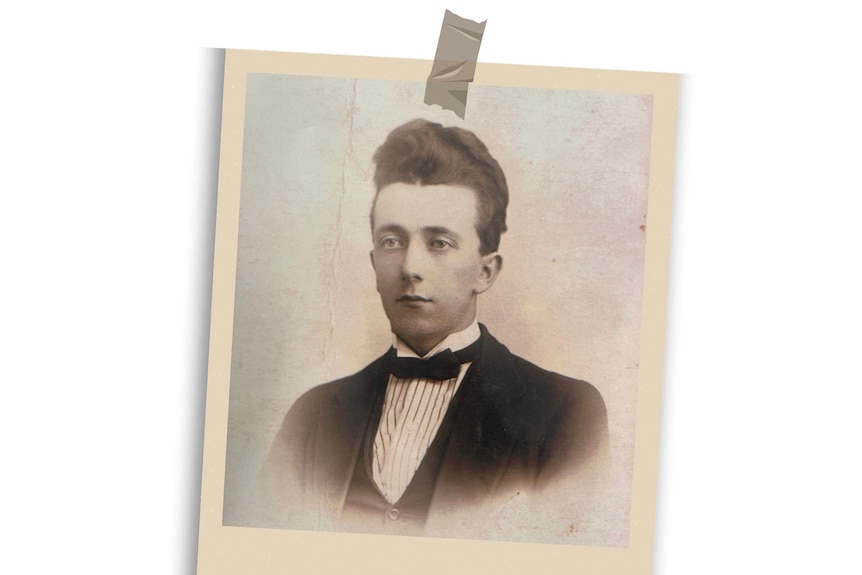 A sepia toned photo in a polaroid style frame of a young man with dark hair in a striped shirt, suit and bowtie