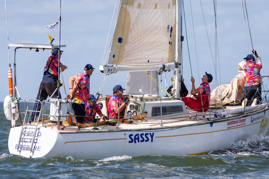 Sailors dressed in pink hawain shirts on a yacht named Sassy. 