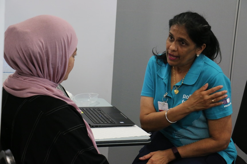 A woman from a CALD community speaks to a staff member at a vaccination clinic.