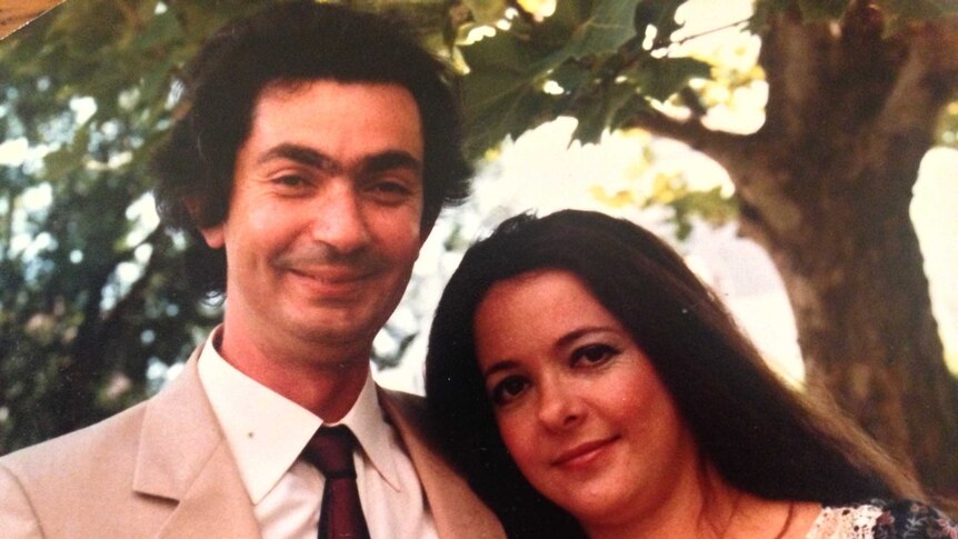 Robert Manne in a suit and Anne Manne in a white-and-red-sleeved dress, by his side.