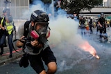 A member of media tries to get away from tear gas during an anti-government demonstration in Hong Kong.