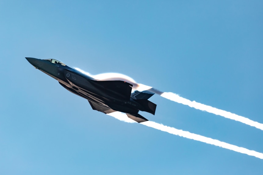 A fighter jet screams through the air, leaving contrails streaming in its wake.