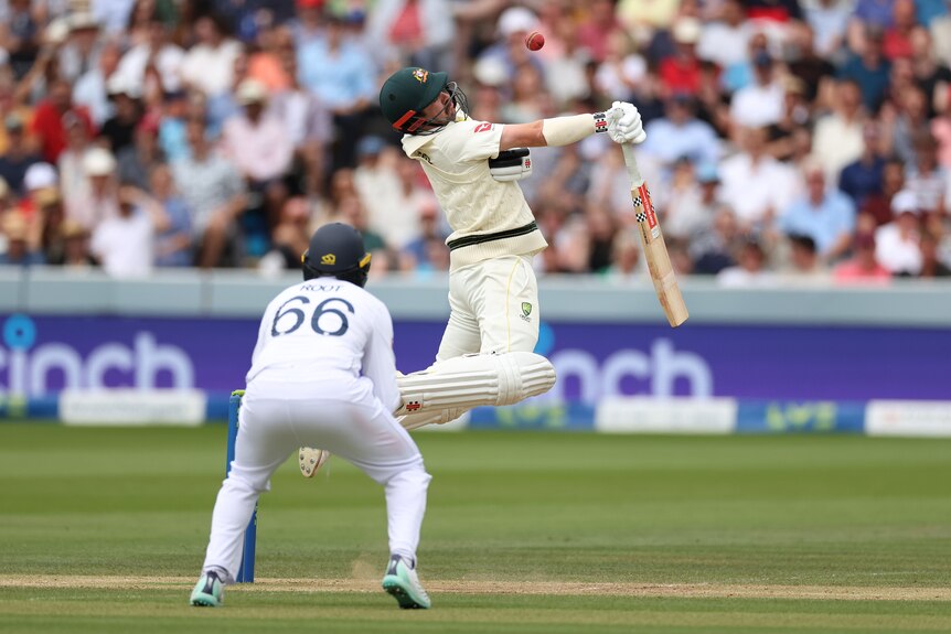 Australia batter Travis Head jumps and avoids a bouncer during an Ashes Test.