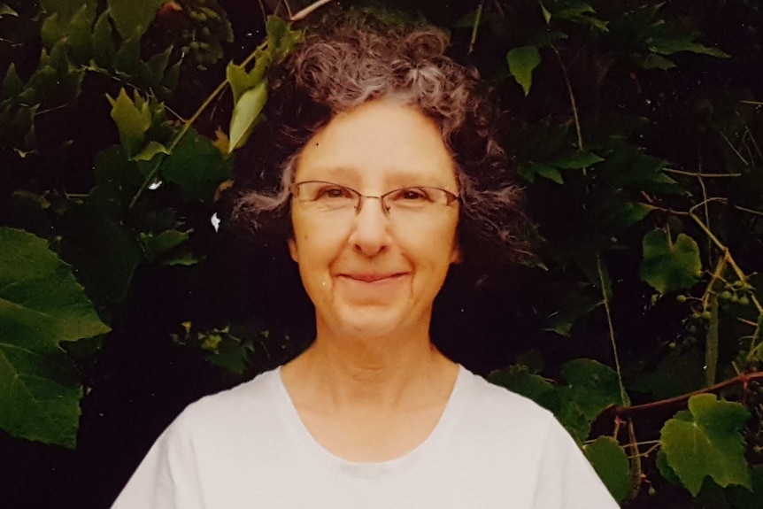 Annabelle Ciufo stands, smiling, in front of a leafy vine.