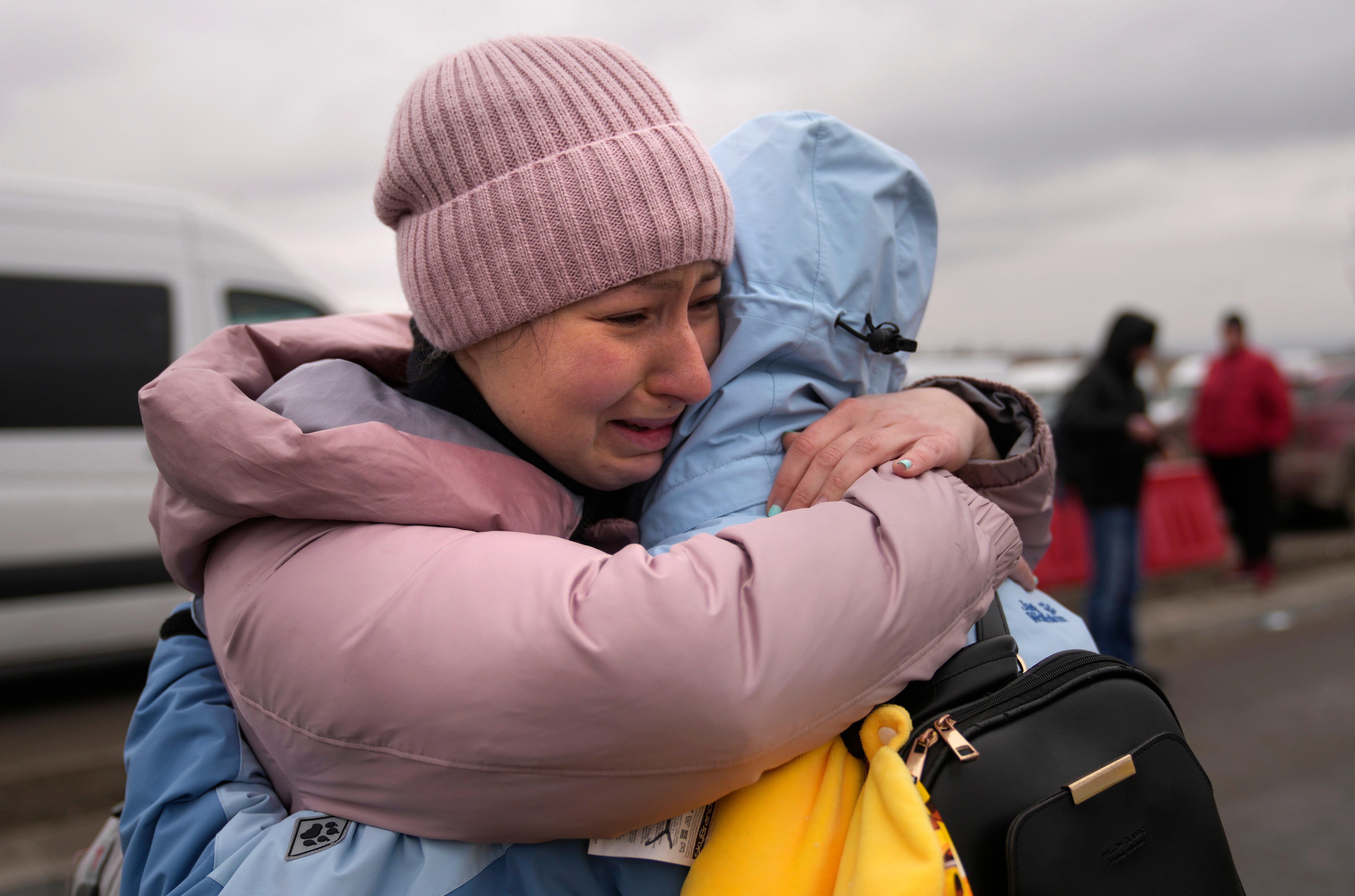 A woman weeps after finding a friend, who also fled Ukraine, at the border crossing in Poland