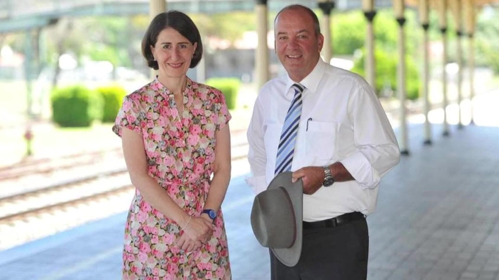 a man wearing a floral dress standing next to a man holding a hat
