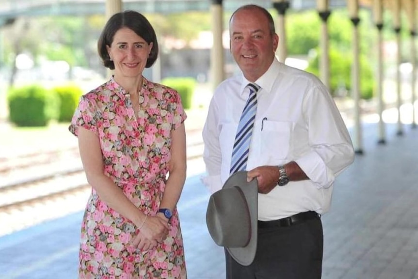 a man wearing a floral dress standing next to a man holding a hat